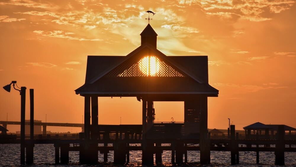 Sun setting through a pier gazebo over the Mississippi Sound