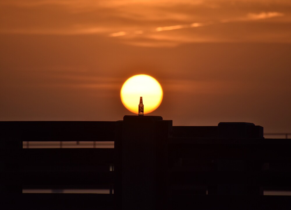 Large sun setting behind a pier silhouette