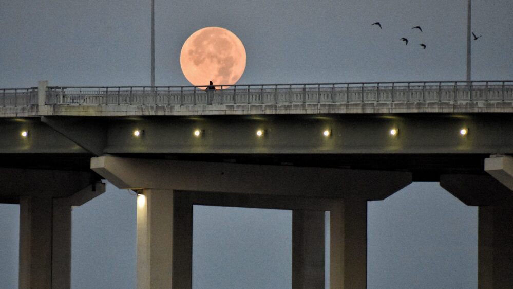Full supermoon rising over the lit bay bridge